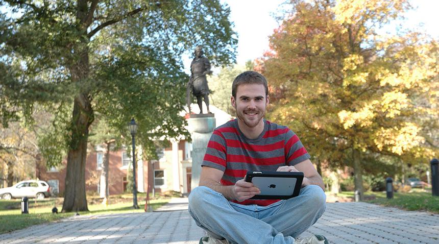Student sitting outside working on a tablet