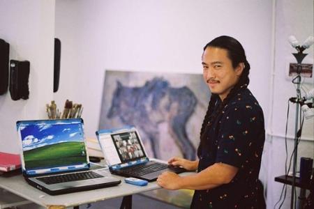 image of the artist in a studio standing in front of two painted laptops